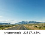 Beautiful road landscape with road signs, mountains, highway and blue sky with fluffy clouds on a sunny summer day. American landscape with a wide highway
