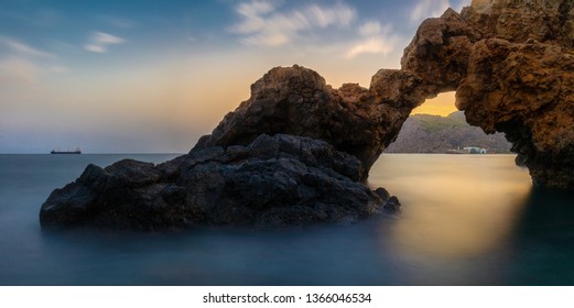 A beautiful rock arch overlooking the sea after sunset with beautiful colors and soft waves photographed with long exposure - Powered by Shutterstock