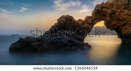 A beautiful rock arch overlooking the sea after sunset with beautiful colors and soft waves photographed with long exposure