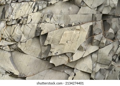 A beautiful rock surface composed of fractured layered mudstone of natural gray color. Texture. Copy space.                               