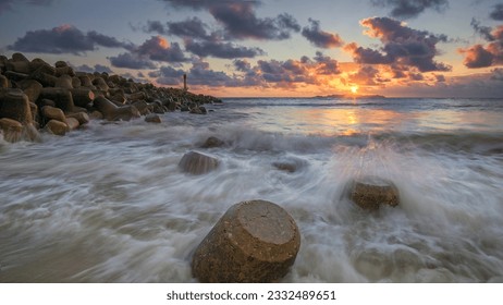 Beautiful rocks texture with light house and a breakwater barrier located at Chendering Beach, Terengganu Malaysia. Slow shutter speed effect. - Powered by Shutterstock