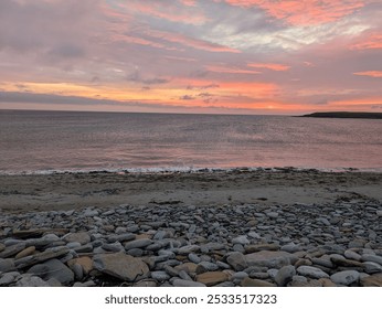 A beautiful rocky beach at sunset with a vibrant sky and calm ocean waves. - Powered by Shutterstock