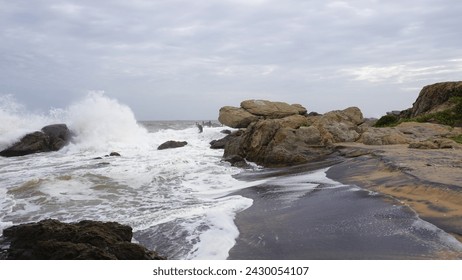 Beautiful rocky shore of muttom beach with sea waves in yellow and black sand. - Powered by Shutterstock