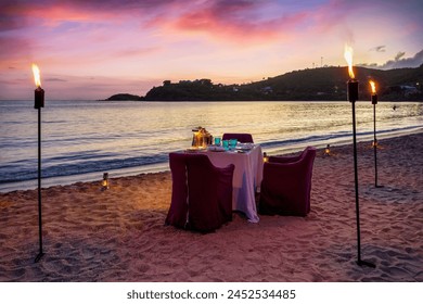 A beautiful, romantic candelight dinner setup at a tropical beach during sunset time