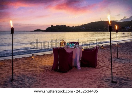 A beautiful, romantic candelight dinner setup at a tropical beach during sunset time