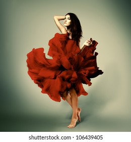 beautiful romantic girl in red flower dress with long broun hair barefoot, full length studio portrait