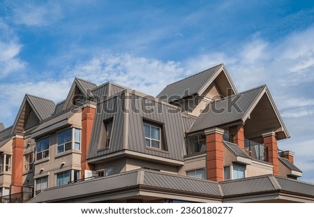 Beautiful rooftop. Modern house , gray metal tiled roof, rain gutter and gable and valley type of roof construction. Roofing Construction. New roof of the house with nice window under the blue sky