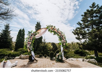 A Beautiful Round Wedding Arch, Decorated With Flowers And Fabric, Stands In A Park, A Garden In Nature. Festive Photo.