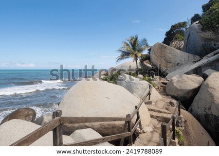 Beautiful roustic stairs of a trekking path at colombian national tayrona park with big rocks and caribbean ocean at background in sunny day