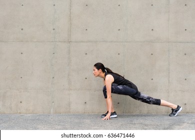 Beautiful Runner Woman Stretching Legs With Lunge Warm Up Motion Relaxing On Gray Background Park Outdoor Road Before Training Cardio Running.