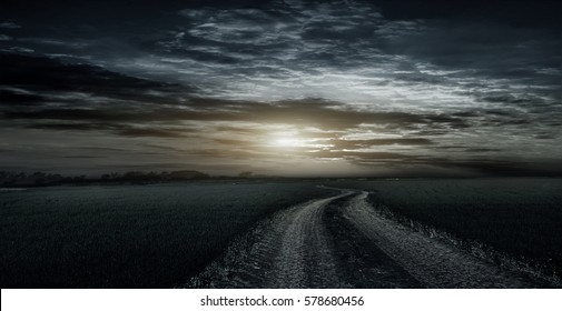  Beautiful, rural, dirt road between fields late at night on the background of beautiful sunset clouds.