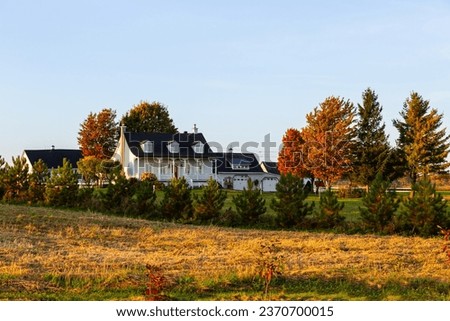 Beautiful rural landscape with French style patrimonial house and barns seen during a late afternoon golden hour, Quebec City, Quebec, Canada