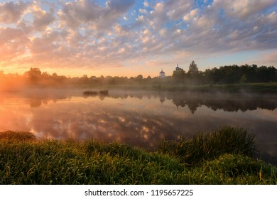Beautiful rural landscape in morning fog at sunrise. Temple on the river bank at sunrise, reflected in the river. Traditional Russian landscape. Klyazma River, Moscow Region, Russia