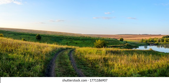 Beautiful rural road nature landscape.Sunny view of green meadows,river and golden wheat fields with trees on a background.Warm colors nature sunset scene.Valley of river Upa in Tula region,Russia. - Powered by Shutterstock