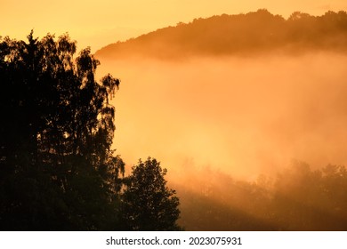 Beautiful Rural Summer Landscape With Trees, Fog And A Hill During Sunset. Seen In Germany In The Rhön Mountains Near Gersfeld In Summer