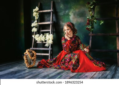 A Beautiful Russian Girl In A Kokoshnik And In Traditional Dress Sits At The Samovar And Eats Bagels. Russian Folk, Retro, Ethno. Pavlovo Posad Shawl. Selective Focus Photo