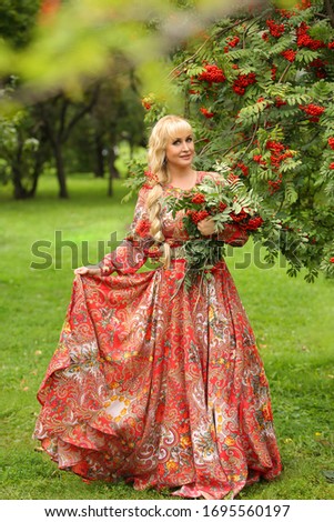 beautiful Russian woman in folk dress with long blond hair in an Apple orchard 