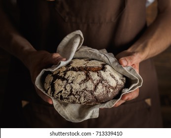 Beautiful Rye bread in a strong bakers hands, wooden wall on a background, rustic photography. horizontal photo close up - Powered by Shutterstock