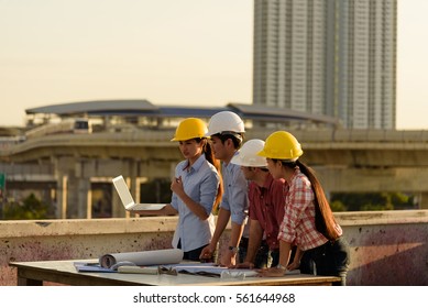 Beautiful Salesperson Presents Project For Foreign Investor And Their Engineers On Top Of Terrace In Construction Site