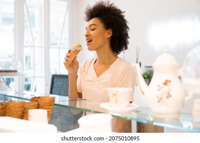 A Beautiful Saleswoman In An Ice Cream Parlor Is Eating Ice Cream.