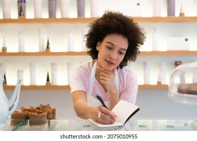 A Beautiful Saleswoman In An Ice Cream Parlor Writes Down An Order.