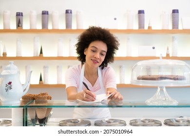 A Beautiful Saleswoman In An Ice Cream Parlor Writes Down An Order.