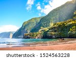 Beautiful sandy beach in Seixal, Madeira Island, Portugal. Green hills covered by tropical forest in the background. People on the beach. Summer vacation destination. Portuguese landscape