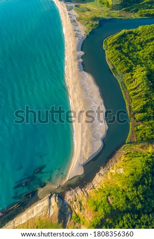 Beautiful sandy beach surrounded by sea waves on one side and on the other by the waters of a river that flows into the sea, the mouth of Veleka River at the Black sea coast, Bulgaria