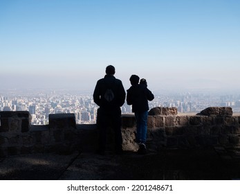 Beautiful Santiago City View From San Cristóbal Hill, At Chile. Foggy Landscape At The City. Back Silhouette View Of Familly Watching The City.