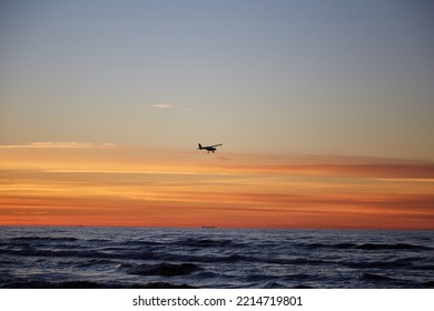 Beautiful Scenary With A Sunset And A Small Plane In The Sky Above The Sea, Selective Focus. High Quality Photo