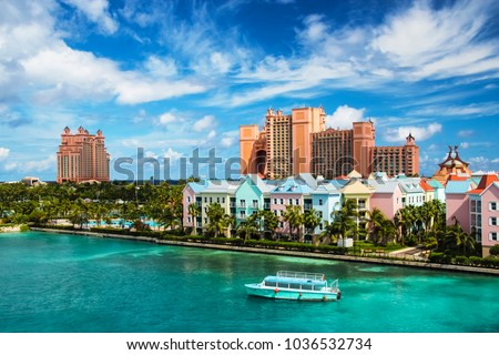Beautiful scene of a boat, ocean, colorful houses and a hotel in Nassau, Bahamas on a summer sunny day