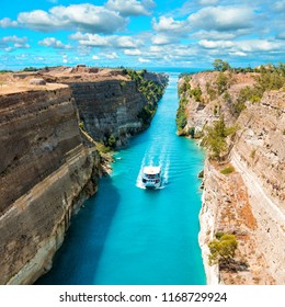 Beautiful scenery of the Corinth Canal in a bright sunny day against a blue sky with white clouds. Among the rocks floating white ship in turquoise water. 