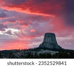A beautiful scenery of Devils Tower rock formation with a pink sunset in the cloudy sky