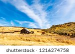 Beautiful scenery of a fenced abandon house and machinery with a beautiful mountains while heading towards Pocatello in Idaho off the I-15 Freeway on the old 191 highway.