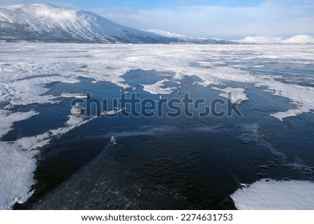 Beautiful scenery of frozen lake Torneträsk (Tornestrask) around Abisko National Park (Abisko nationalpark). Deep cracks in the ice sheet.  Sweden, Arctic Circle, Swedish Lapland