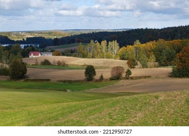 Beautiful scenery of kashubian landscape with fields and trees on hills in autumn scenery. Little house with red roof among fields. Around Sierakowice, Kashubia, Poland
