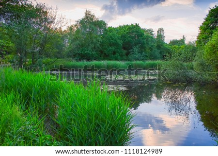 Beautiful scenery of Staffordshire, Uk.Westport lake nature reserve in woodland near Stoke on Trent, Uk on summer day.Calm and tranquil place.Scenic landscape uk.Sky reflection in water.Serenity.