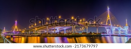 Beautiful scenic of light up on the highway bridge across the river with the garden and open dam in Thailand called industrial ring road. (Bhumibol bridge, Samut Prakan)