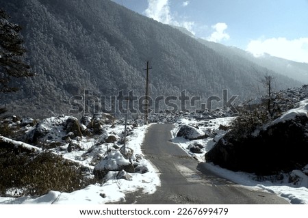 Beautiful scenic mountains road on the way from Lachung to Zero point (Yumesamdong)  Mountains road, Sikkim. Mountain with snow and leaves fewer trees. Below with dirt road.