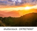 beautiful scenic sunset landscape of a canyon between two mountains with green  bush rocks on foreground and amazing walley with bright cloudy sky on background