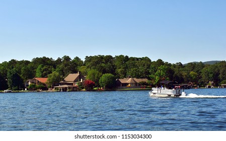 Beautiful scenic view of lake houses on the shoreline with a pontoon boat in the water.