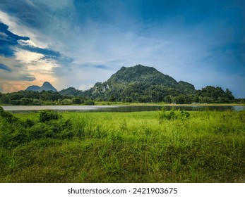 A beautiful Scenic view of the mountain with green grass and a calm lake with cloudy blue sky background at tasik timah tasoh, perlis, malaysia.
 - Powered by Shutterstock