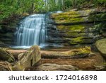 The beautiful and scenic waterfall Long creek falls in the north Georgia mountains with rocks boulders and a log and surrounding forest in springtime