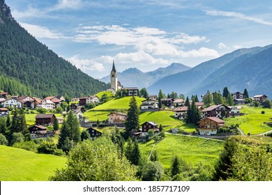 Beautiful Schmitten village at Albula pass in Grisons, Graubuenden, Switzerland with view of houses on green grassy hills, a lovely church on hilltop and majestic mountains in background - Shutterstock ID 1857717109