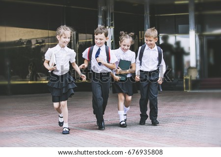 Beautiful school children active and happy on the background of school in uniform