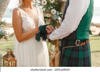 Beautiful Scottish Couple Groom And Bride. National Traditional Clothing - Kilt. Couple Holding Hands During Wedding Ceremony