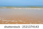 Beautiful sea with sand, yachts, waves on the water and blue sky. Natural background for summer vacation.