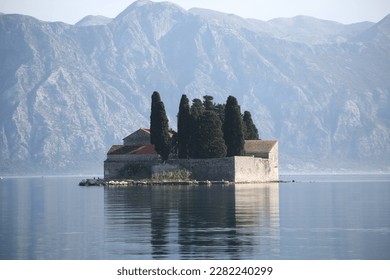 Beautiful seascape in the famous place of Montenegro with beautiful islands and churches, stone walls of the fortress, views of the sea and snowy, blue rocks and mountains, houses with red r