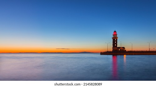 A beautiful seascape with lighthouse against blue sky with an orange sunset light on horizon. Tourist berth in Turka port on Baikal Lake. Natural background. Mock up with empty space for text