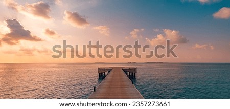 Beautiful seascape long jetty pier at sunset. Minimal sea sky, calm water surface and reflections. Colorful peaceful sunrise tones orange, gold, blue. Tranquil relaxing panoramic inspire meditation